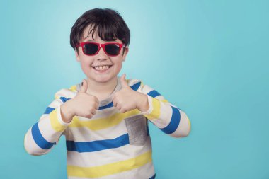 mavi arka plan üzerinde güneş gözlüğü ile boy gülümseyerek