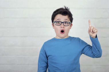 tuğla zemin üzerine işaret eden oktan yukarı işaret parmağı ile el yükselterek gözlüklü çocuk