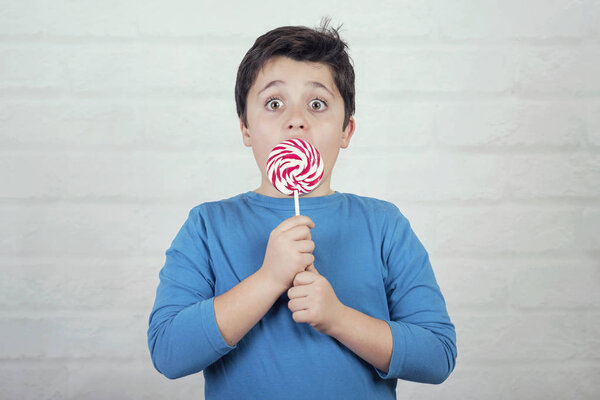 surprised child with lollipop on brick backgroun