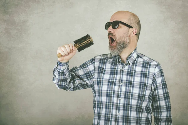 Homme avec des lunettes de soleil chantant une brosse à cheveux — Photo