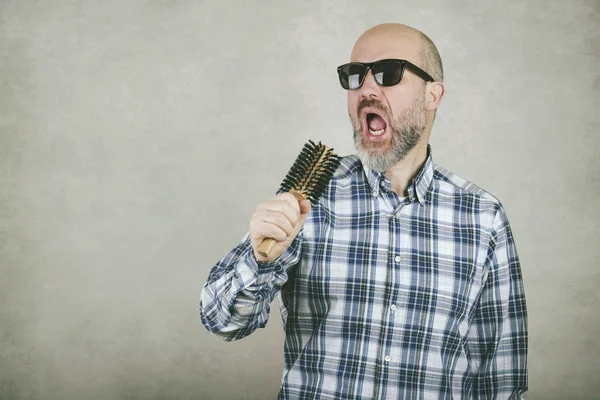 Homme chauve avec des lunettes de soleil chantant une brosse à cheveux — Photo