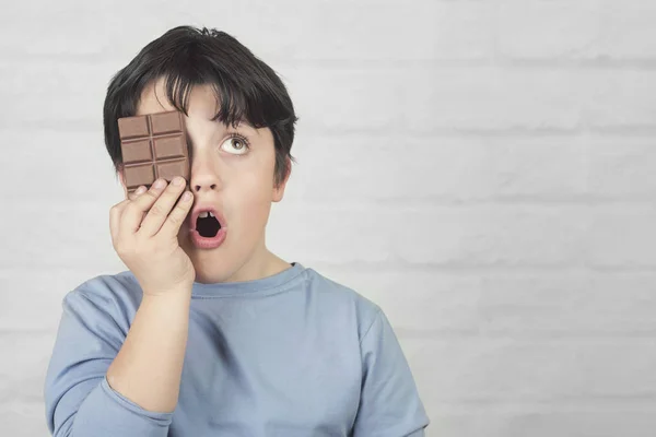 Niño que cubre un ojo con una barra de chocolate — Foto de Stock