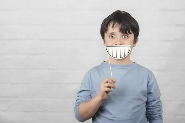Смешной и улыбающийся ребенок с картонной улыбкой — стоковое фото