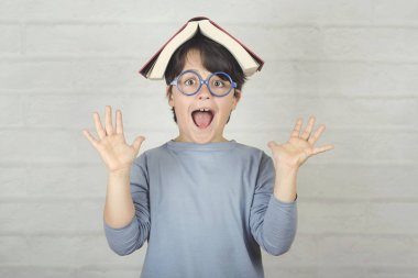 başında kitap ile mutlu ve gülümseyen çocuk