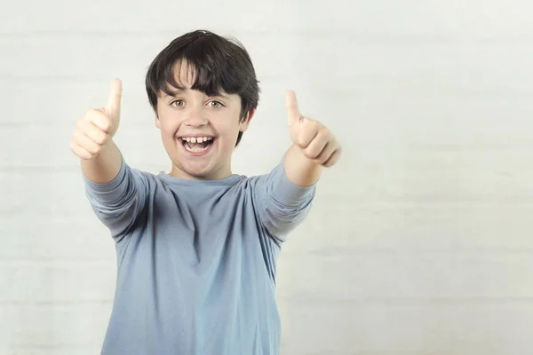Pequeño niño sonriendo mostrando pulgares hacia arriba — Foto de Stock