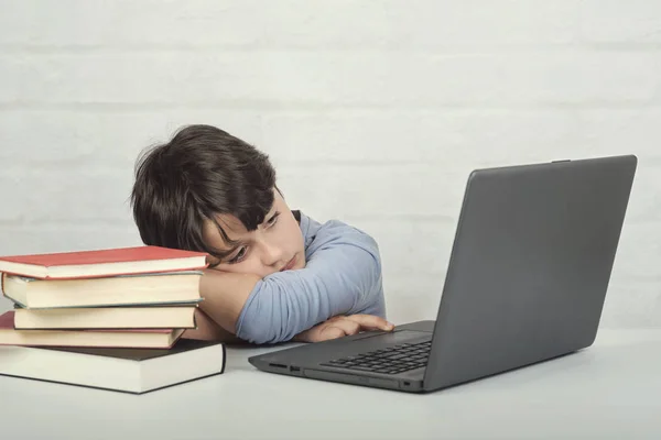 sad boy with laptop computer and books