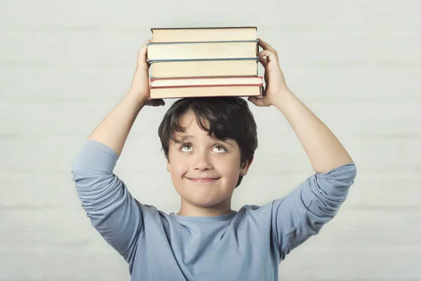 Criança feliz e sorridente com livros na cabeça — Fotografia de Stock