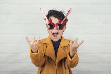 ellerle rock sembolü yapan güneş gözlüğü olan çocuk