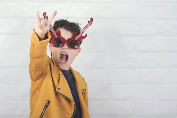 Enfant avec des lunettes de soleil faisant symbole rock avec les mains en l'air — Photo