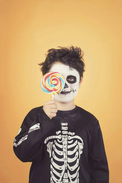 Szczęśliwy Halloween. śmieszne dziecko w kostium szkielet obejmujące oko z Lizak — Zdjęcie stockowe