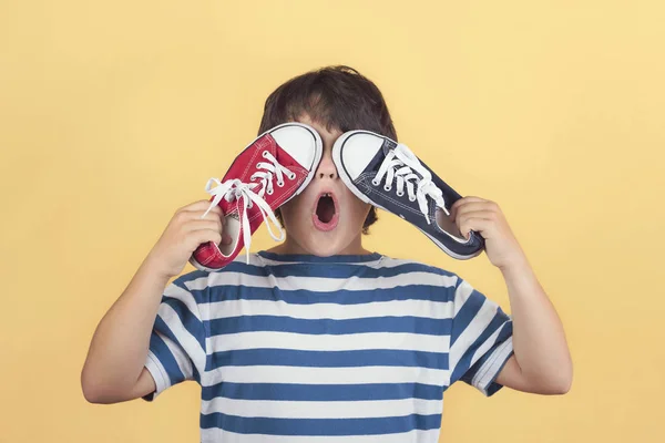 Niño gracioso que cubre los ojos con unas zapatillas — Foto de Stock