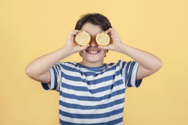 gülümseyen çocuk gözlerinin üzerinde limon tutan