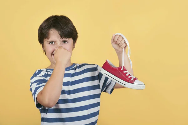 Niño sosteniendo zapatillas olorosas zapatos — Foto de Stock