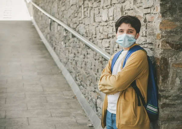 医療マスクとリュックを持った子供が学校のドアの外で待っています — ストック写真