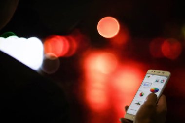 Arka planı bulanık bir cep telefonunu tutan bir el.