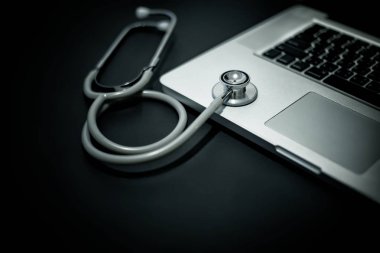 Siyah arkaplanda steteskop ve dizüstü bilgisayar