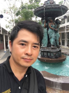 Genç adam çeşmenin yanında poz veriyor. 