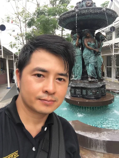 Genç adam çeşmenin yanında poz veriyor. 