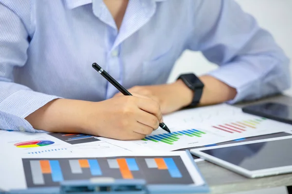 Side View Of Graph Papers On Table and business people writing on paperwork