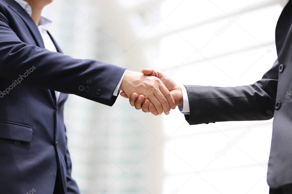 midsection of two business people shaking hands in outdoor