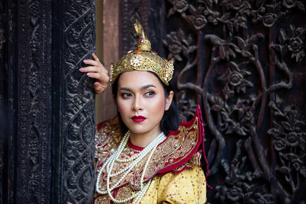マンダレーのアジア人女性の肖像画 金色の伝統服を着たミャンマーの女性が木製のドアを彫る美術に立ち向かう — ストック写真