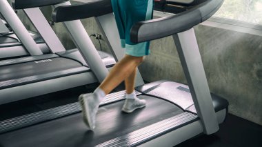 Spor kıyafetli bir kadın spor salonunda antrenman yapıyor.