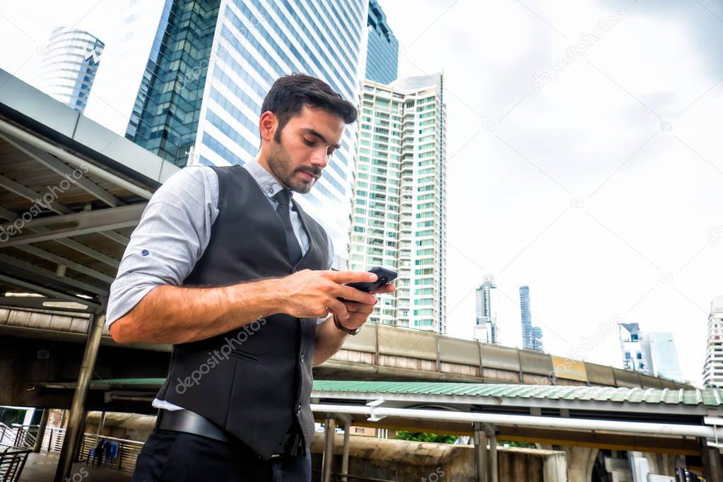 portrait of a young businessman in suit using smartphone in city