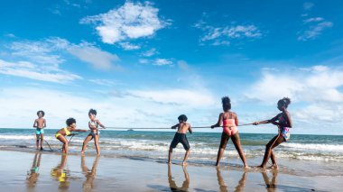 Çocuklar kumsalda kumda koşuyor.