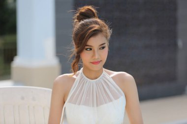 Gelinlik giymiş, saçları kıvırcık, güzel, çekici, gülümseyen bir kadın resmi..