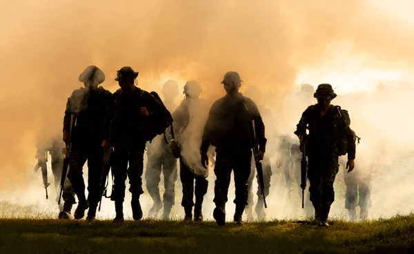 ライフルを持った認識できない兵士のシルエット煙 黄色の煙と日没の背景を歩く — ストック写真