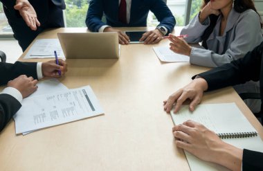 Genç iş adamları ofiste birlikte çalışıyorlar. Yönetici bir tabloya işaret ediyor ve iş stratejileri hakkındaki analizleri açıklıyor. İş dünyasının en iyi el sıkışması.