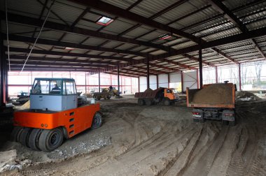 Bir hangar binası, bir kazıcı ve çöp kamyonları yüklendi.