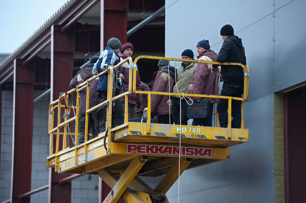 At the construction site. Workers standing on the platform of the truck mounted lift going up