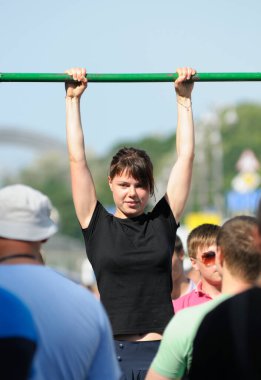 Sokakta yatay bar setinde egzersiz yapan bir kız, insanlar izliyor. 3 Haziran 2018. Kiev, Ukrayna