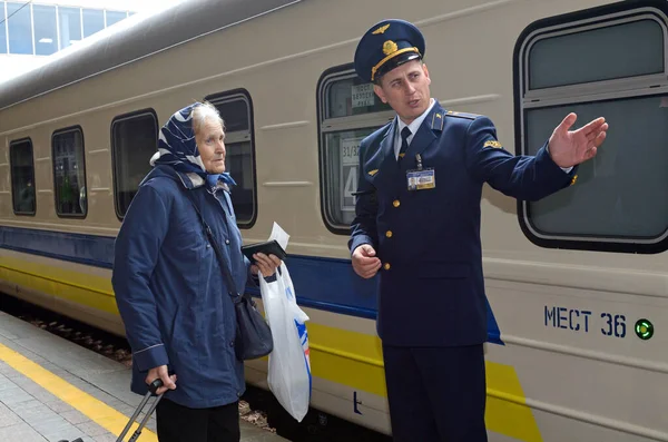 Kondüktör, eski bir yolcunun arka planda kompartımana giden yolu gösteriyor. 1 Ekim 2018. Grand Central tren istasyonu. Kiev, Ukrayna