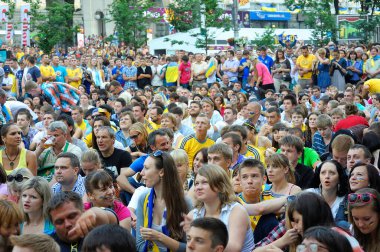 Bir sürü insan kaldırım kenarında oturmuş futbol maçını seyrediyor. Avrupa-2012. 1 Temmuz 2012. Kiev, Ukrayna