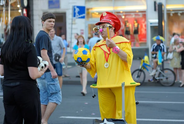 Uliczny Klaun Żółtym Kostiumie Czerwonym Kapeluszu Zabawiający Ludzi Piłką Nożną — Zdjęcie stockowe