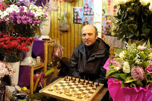 笑顔の男は 花の通りの売り手は チェスの駒 カラフルな花の花束を周りのチェス盤の前に座っている 2019年9月12日 キエフ ウクライナ — ストック写真