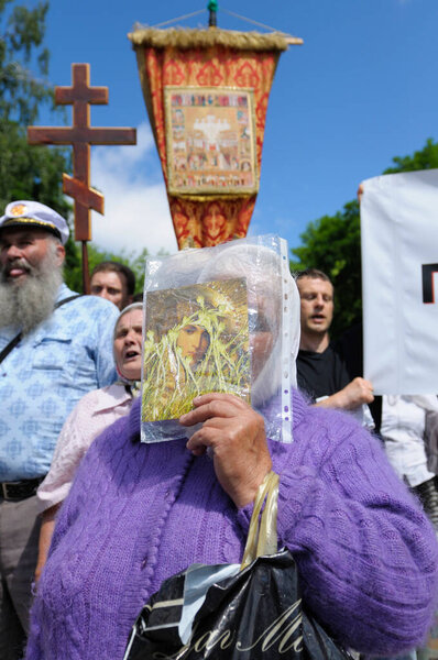 Woman follower of Orthodox Church Moscow Patriarchate hiding her face behind an icon. May 25, 2013. Kiev, Ukraine