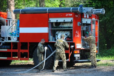 İtfaiye aracı park etmiş, itfaiyeciler yangın söndürme ekipmanlarını kullanıma hazırlıyor. 5 Haziran 2019. 2019. Kievskaya oblast, Ukrayna