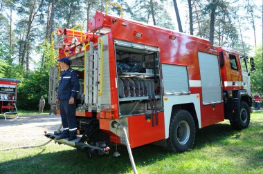 İtfaiye aracı park etmiş, itfaiyeciler yangın söndürme ekipmanlarını kullanıma hazırlıyor. 5 Haziran 2019. 2019. Kievskaya oblast, Ukrayna
