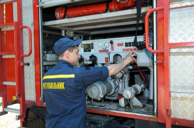 İtfaiyeci su pompası motorunun kontrol paneline dokunarak onu çalıştırdı. 5 Haziran 2019. Kievskaya oblast, Ukrayna