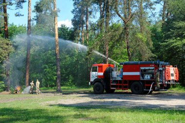 Bir itfaiye aracının su topu yüksek hızlı bir su akıntısını vuruyor, itfaiyeciler ormanda yangınla savaşıyor. 5 Haziran 2019. 2019. Kievskaya oblast, Ukrayna