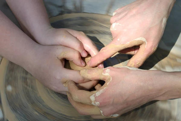 Tekerlek fırlatmayı öğretiyorum. Potter 'ın eli çömlekçinin tekerindeki kilin şeklini düzeltiyor.