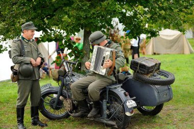 2. Dünya Savaşı 'ndan kalma üniformalı bir Alman askeri eski bir askeri motosiklette oturmuş akordeon çalıyor. 4 Ekim 2012. Kiev, Ukrayna