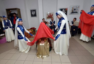 Kırım Tatar geleneksel nikahı: nedimeler bir gelini damat ile buluşmaya hazırlarken kırmızı örtüsünü örterler. Kırım Tatar Kültürü Günleri. 27 Şubat 2019. Kiev, Ukrayna