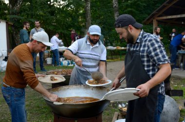 Üç adam kepçeli tabağa haşlanmış et ve pirinç koydu. Ramazan ayı, oruç tutma, oruç tutma. 19 Mayıs 2018. Kiev, Ukrayna