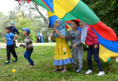 Çimenlikte çocukla oynayan genç bir kadın sokak sanatçısı. Ramazan ayı, oruç tutma, oruç tutma. 19 Mayıs 2018. Kiev, Ukrayna