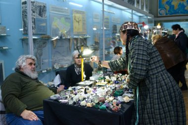 Kadın müşteri tezgahta mücevher seçiyor, satıcıyla konuşuyor.