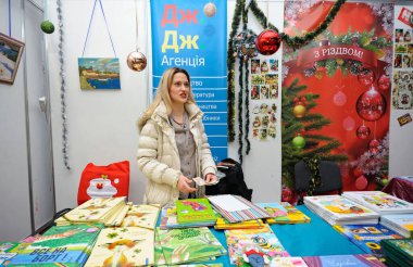 Kitapçı tezgahında müşterileri bekliyor. Kitap Fuarı sözleşmeleri. 14 Aralık 2017. Kiev, Ukrayna